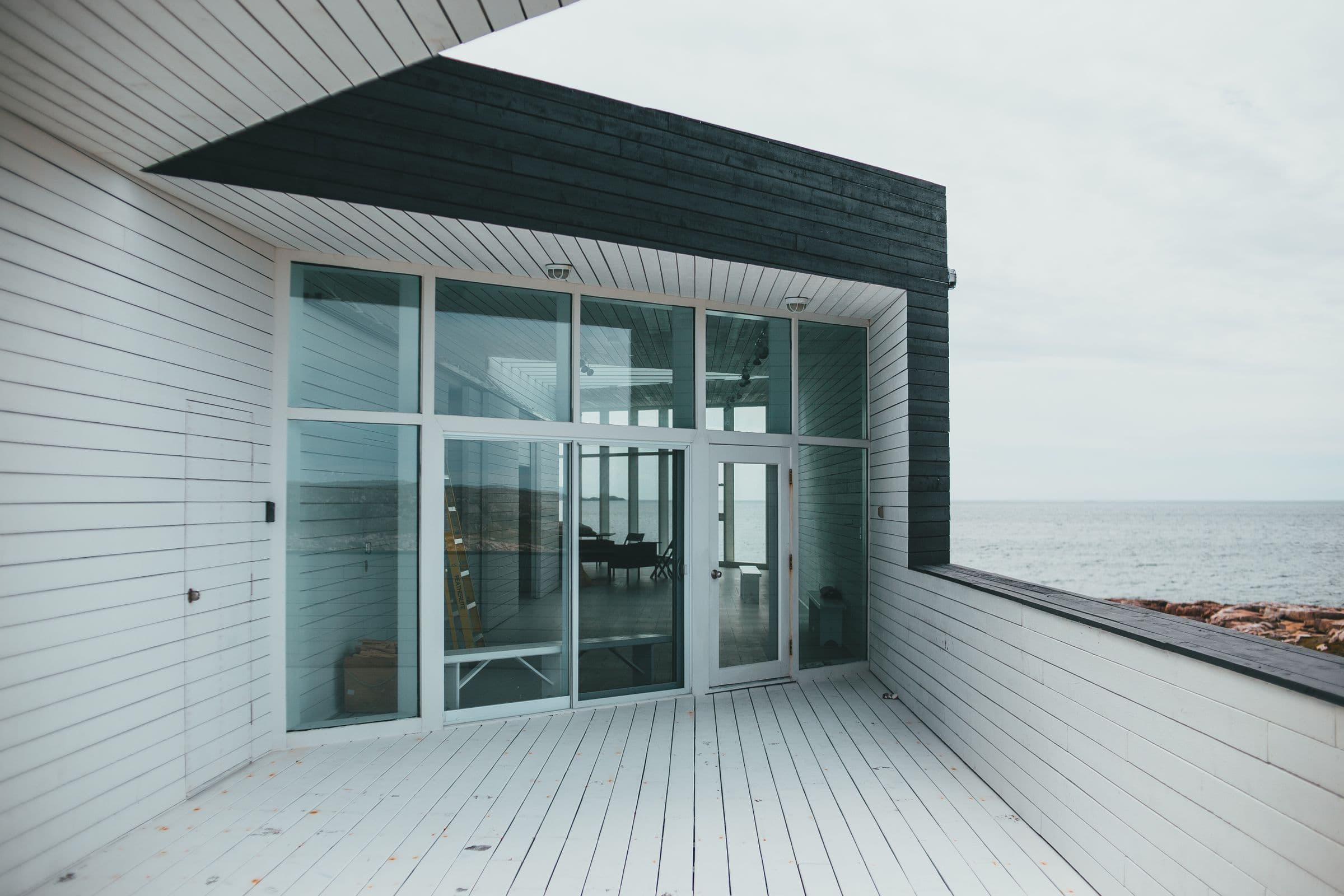 Varanda contemporânea com fechamento de vidro em esquadria de alumínio e vista para o mar